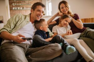 A happy family sitting down to watch a movie together.