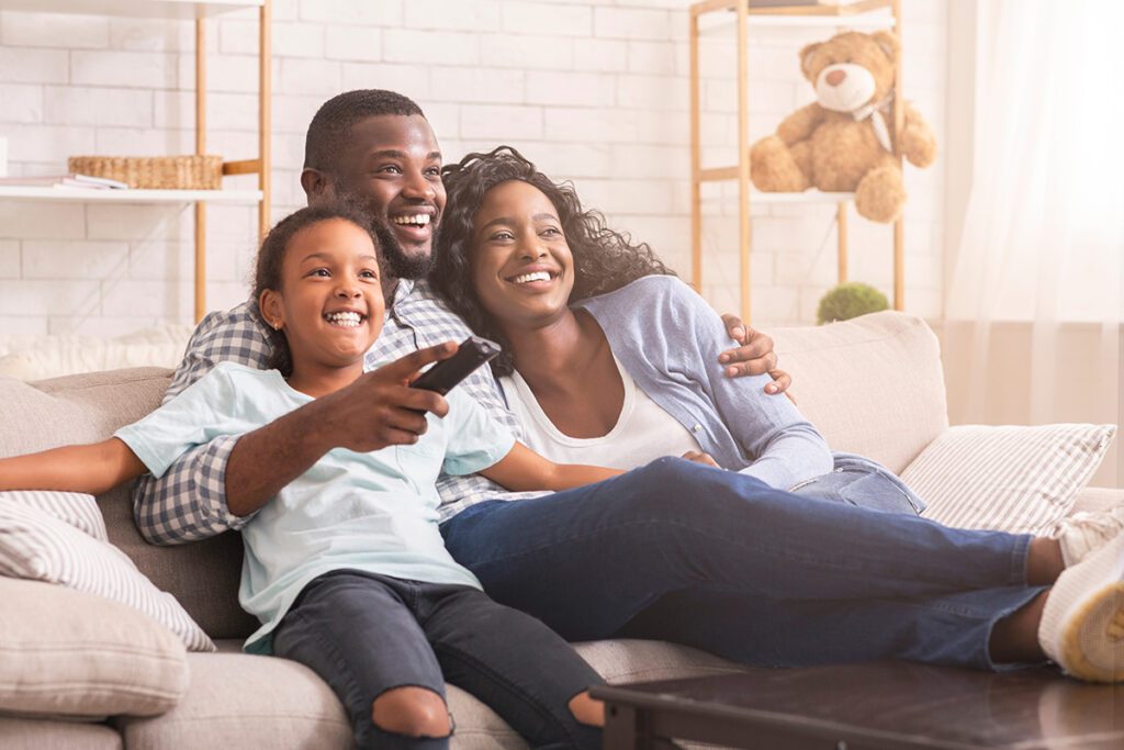 Family watching tv happily together.