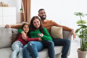 Happy young family watching tv in living room.