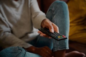 Person holding a TV remote control while streaming family-friendly filtered content on a major streaming service